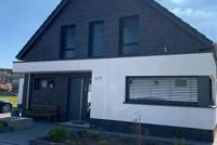 Neubau in Duisburg, modernes Einfamilienhaus mit Satteldach, Erdwärmepumpe, Glattziegel, farbige Dachüberstände, Eckfenster