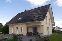 Massivhaus Putzbau in Ibbenbren, NRW, Freisitz Terrasse, hochgezogener Eingangsbereich Glas, Schornstein, Pfettenkpfe