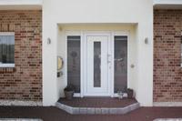 Massivhaus Fertighaus individuell in Lengerich, Westfalen, Eingang überdacht, Lisenen mit Putzstreifen, Erdwärmepumpe